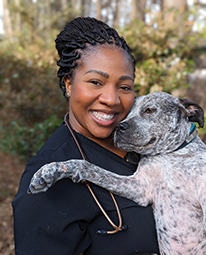 Portrait headshot picture of Dr. Azalia Boyd smiling with a dog in her arms outside