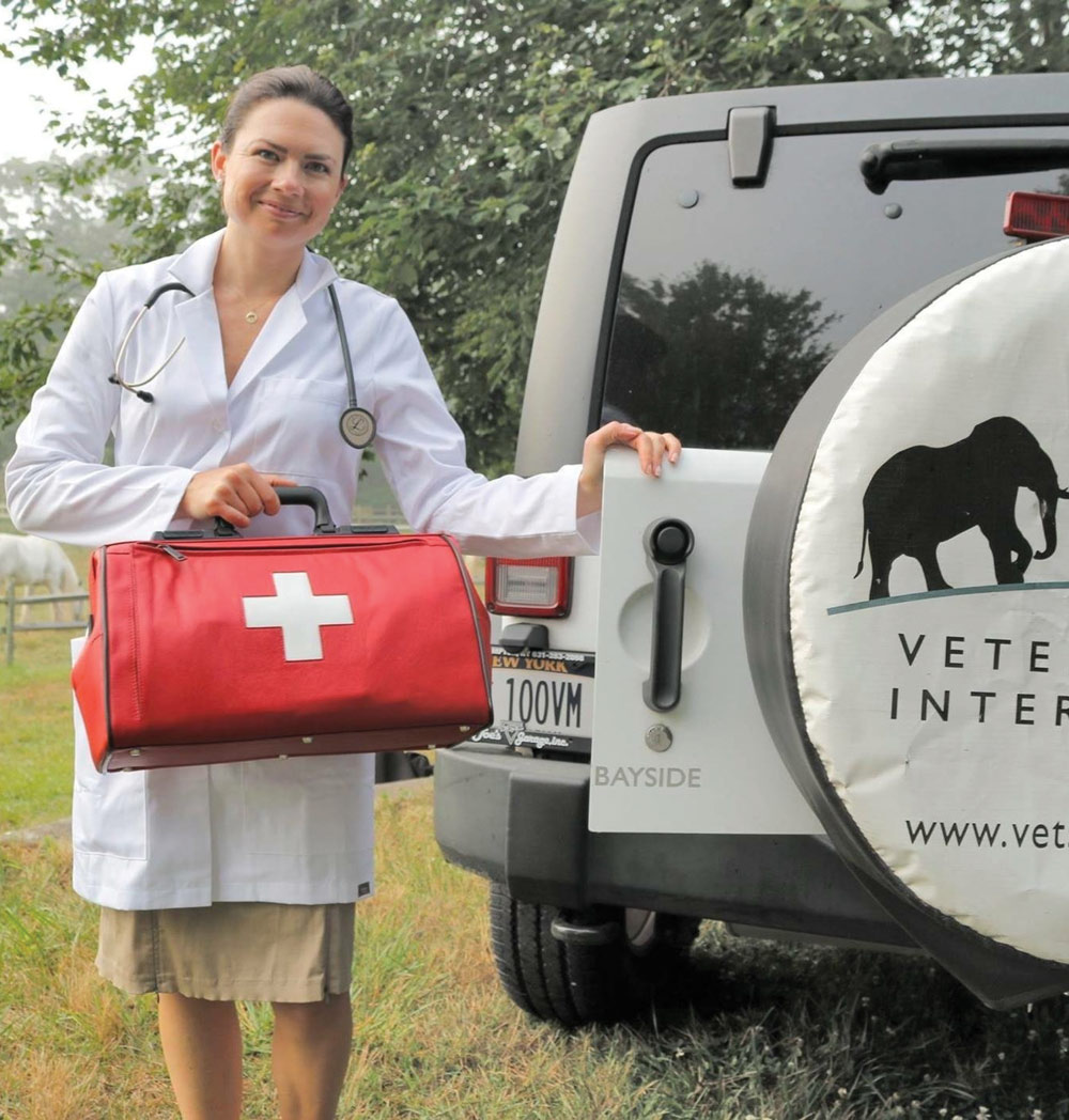 Dr. Magda with a nurses kit standing next to a car