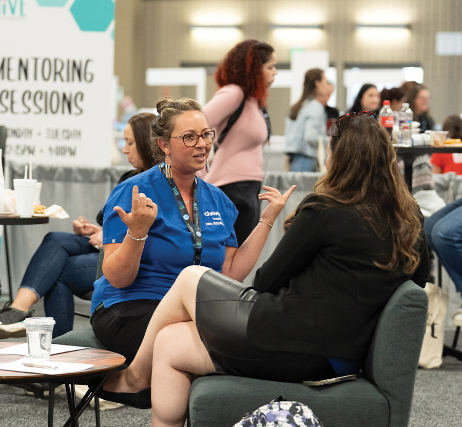 two women seated at a couch and having a conversation at the HiVE Event