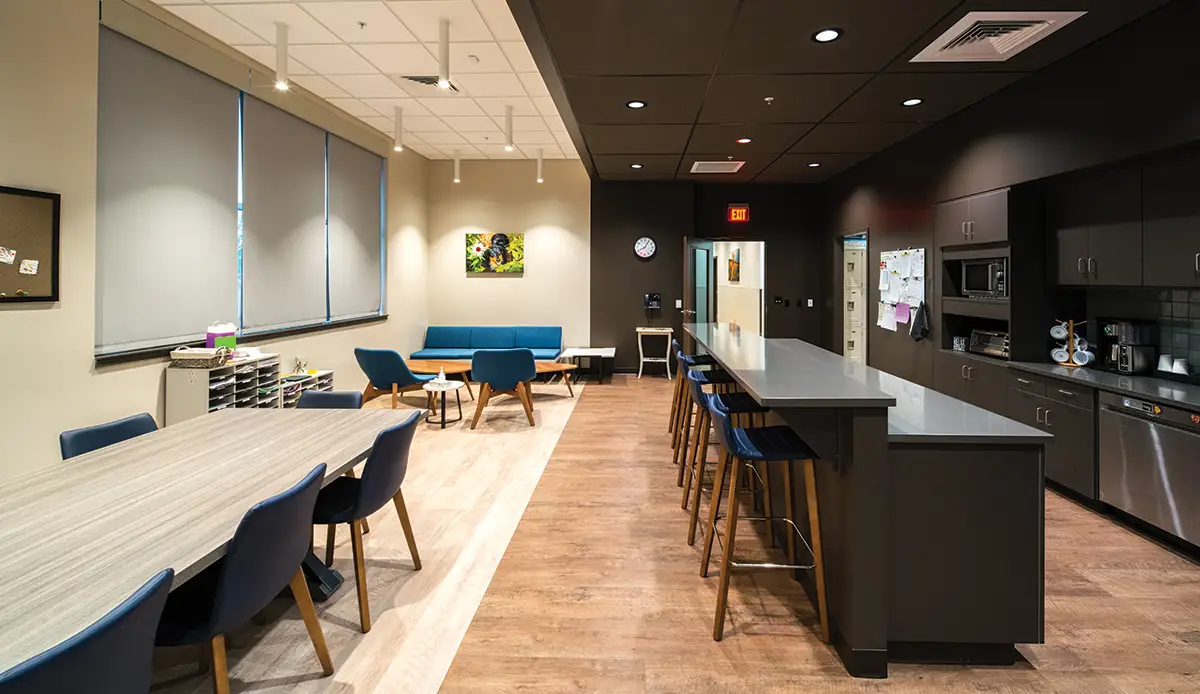 wide view of a clinic break room with various tables and chairs, bar counter, and kitchen